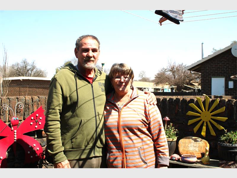 A man and woman standing in front of a fence.