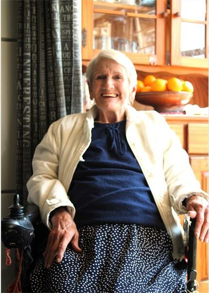 An older woman sitting in a chair with a smile on her face.