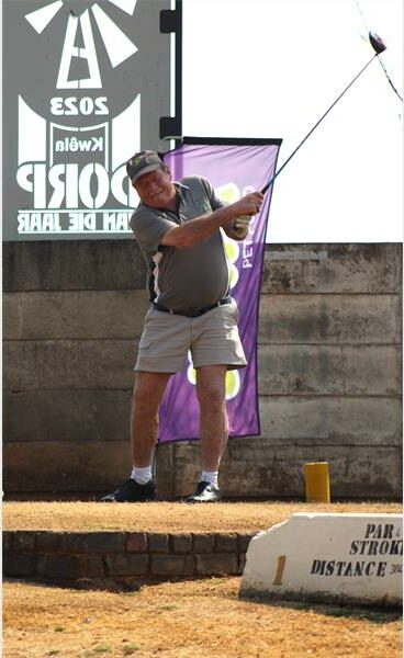 A man is playing golf on a course with a sign.