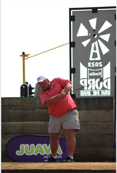 A man is swinging a golf club at a tournament.