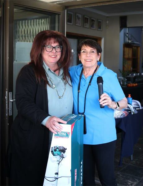 Two women standing next to each other holding a box.