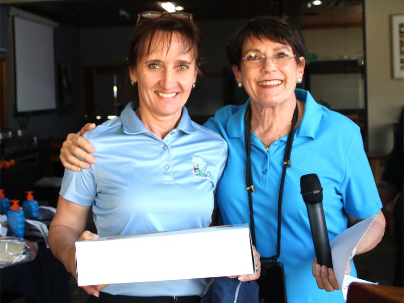 Two women in blue shirts holding a box.