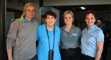 Four women in blue shirts and black shirts posing for a picture.