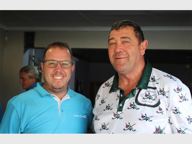 Two men in blue shirts and white shirts standing next to each other.