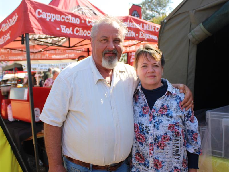 A man and woman standing next to each other at a food stand.