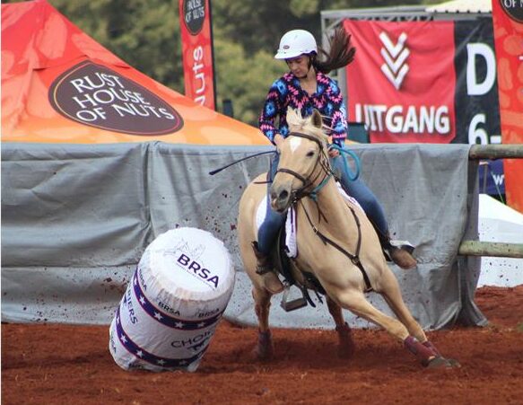 A woman riding a horse around a barrel.