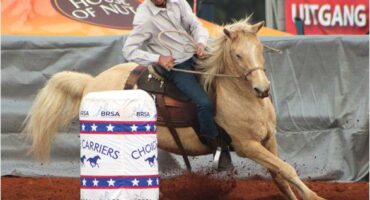 A man riding a horse around a barrel.
