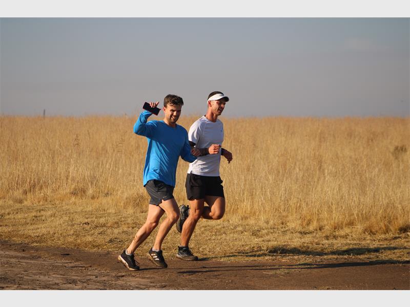 Two men running in the middle of a field.