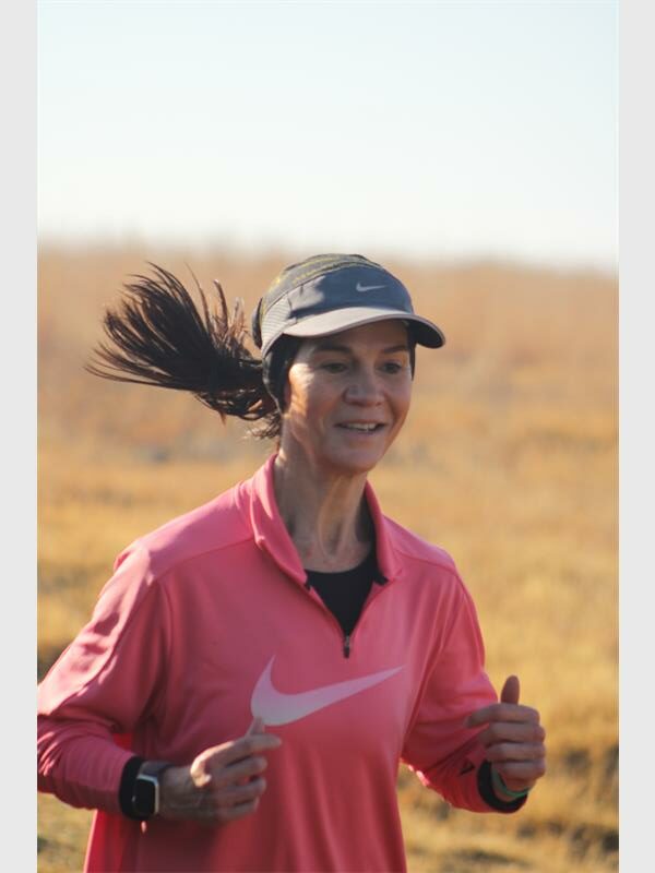 A woman running in a field with her hair blowing in the wind.