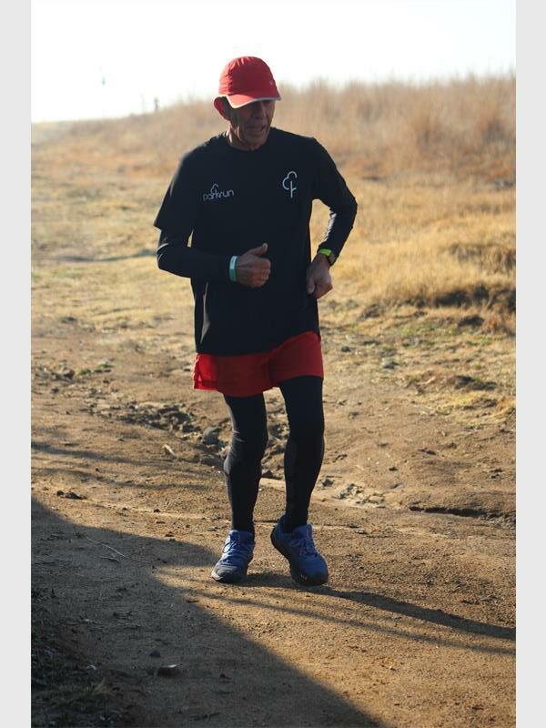 A man in a red hat and black shirt running on a dirt road.