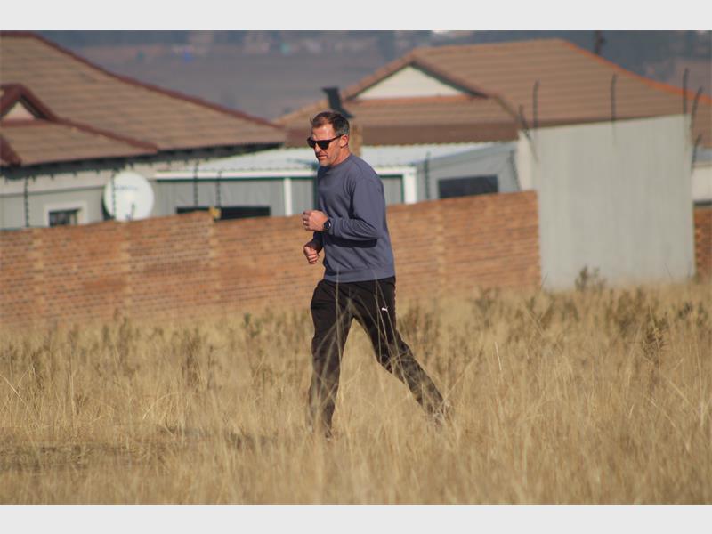 A man running in a field with a house in the background.