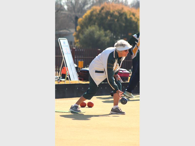 An older woman playing a game of bowls.