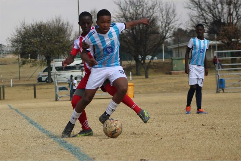 A group of young men playing soccer on a field.