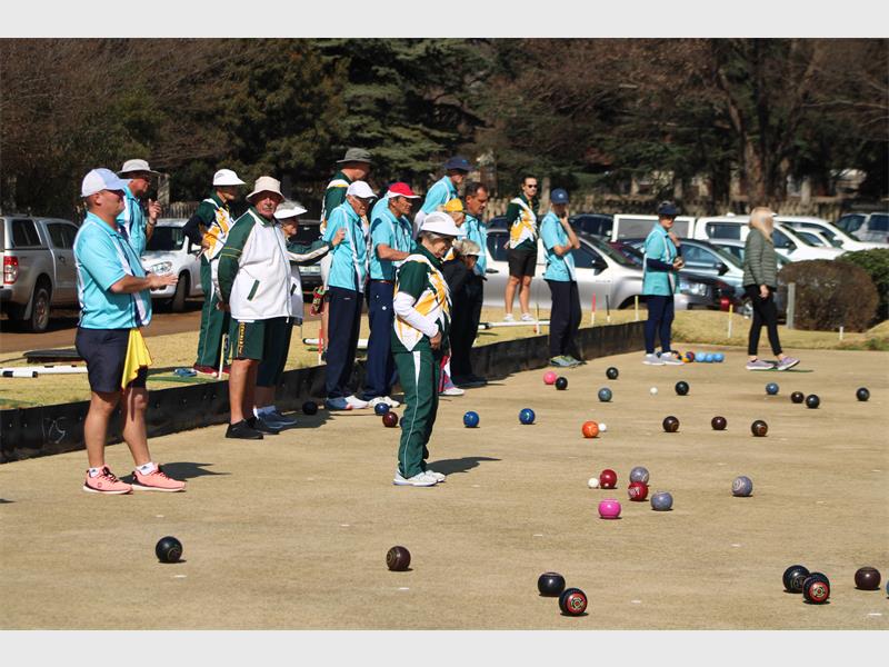 A group of people playing bowls on a field.