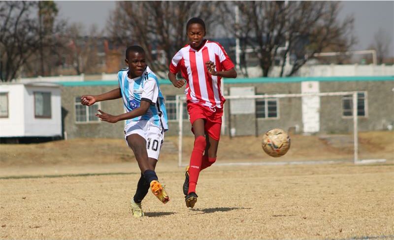 A young boy in a blue and white soccer uniform is about to head the ball.