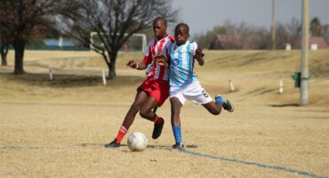 Two boys playing soccer on a field.