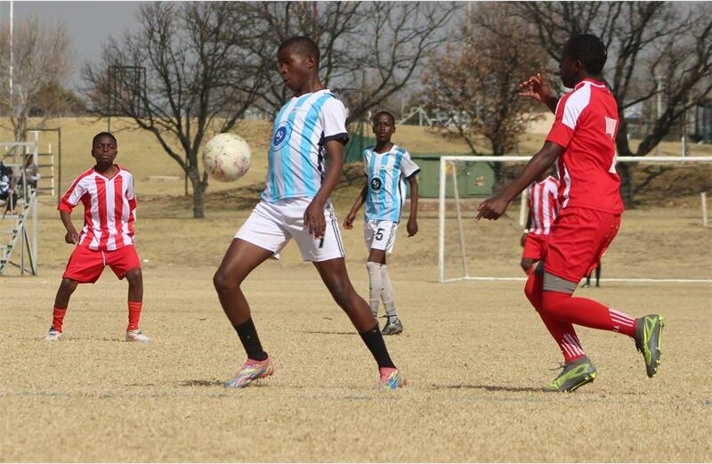 A group of young men playing soccer on a field.