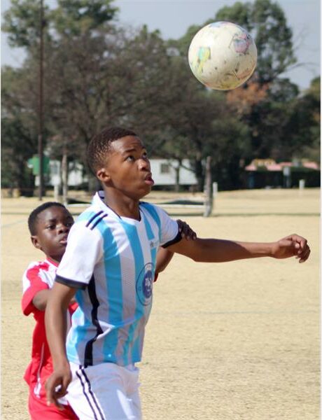A young boy in a blue and white soccer uniform is about to head the ball.