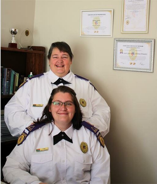 Two women in uniform sitting at a desk.