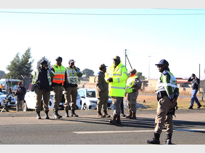 Police officers standing near a road with cars and trucks.
