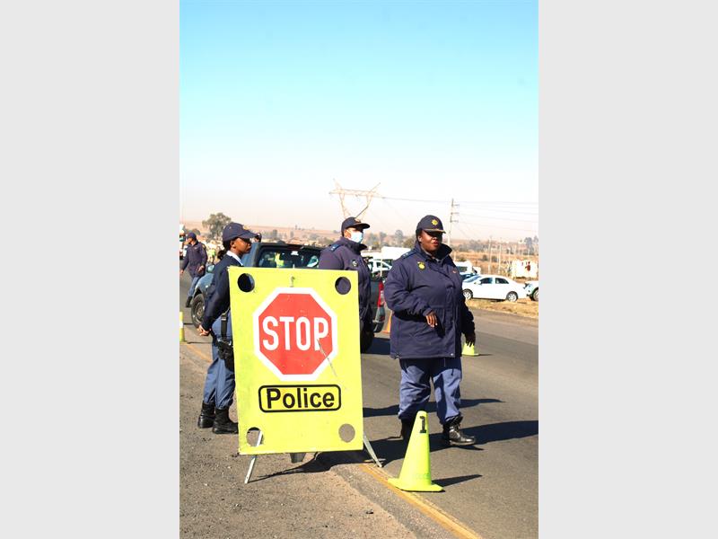 Police officers stand next to a stop sign.