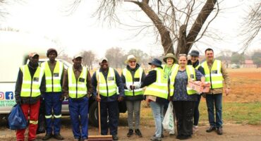 A group of people in safety vests standing next to a truck.
