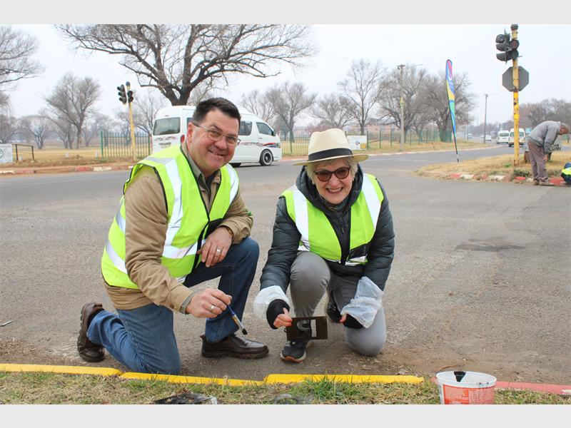 Two people kneeling on the side of the road.