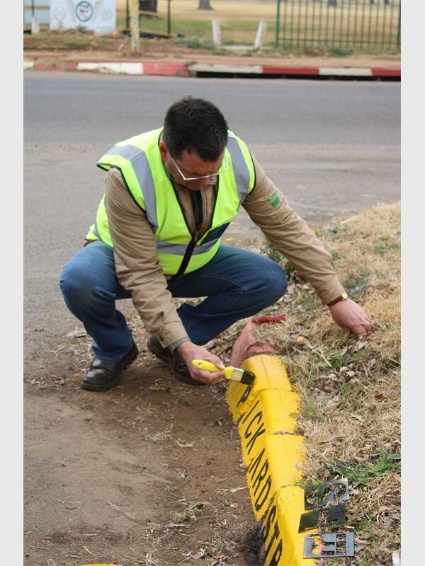 A man kneeling down to inspect a yellow line.