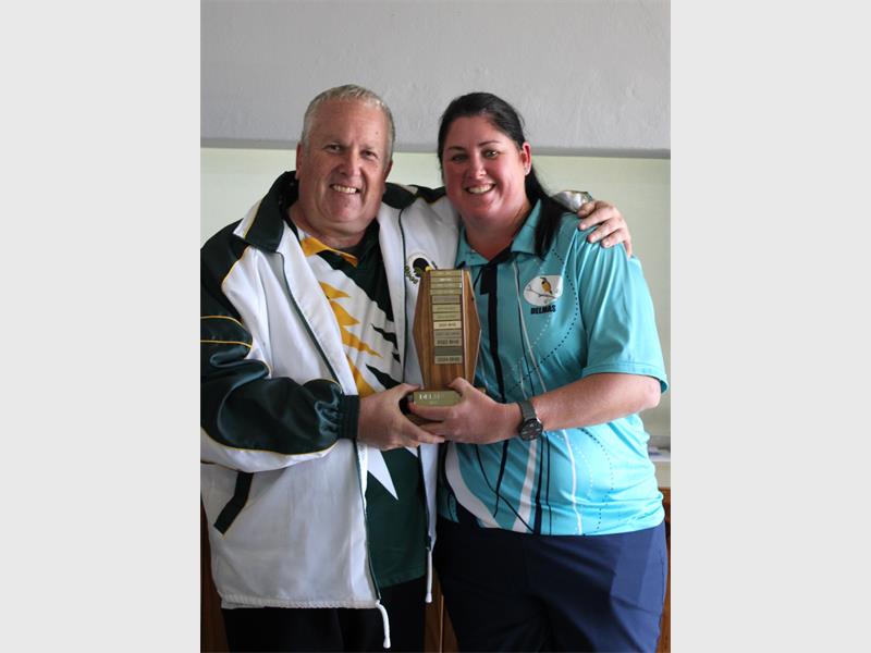 A man and woman holding a trophy in a room.