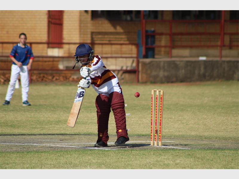 A young boy playing cricket on a field.