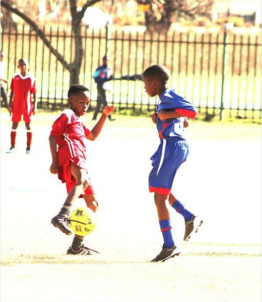 Two boys playing soccer on a field.