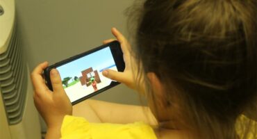 A young girl is playing a video game on her phone.