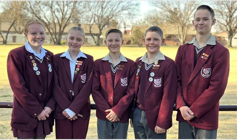 Five young people in school uniforms standing next to each other.