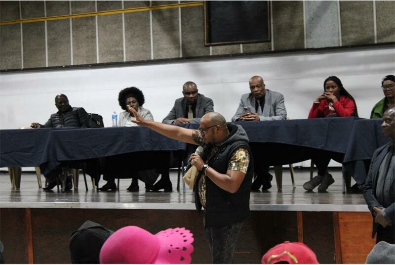 A man speaking at a conference with other people.