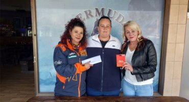 Three people standing in front of a restaurant with a check.