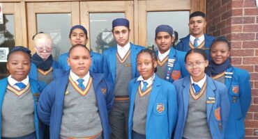 A group of young people in school uniforms standing outside.