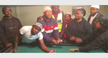 A group of people standing around a pool table.