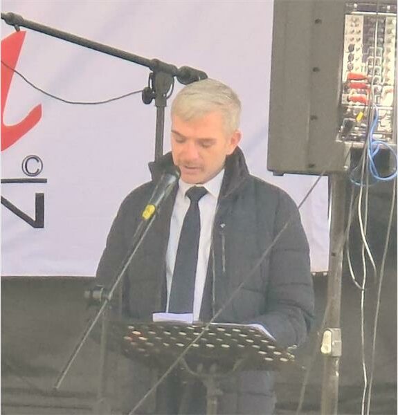 A man in a suit and tie standing at a podium.