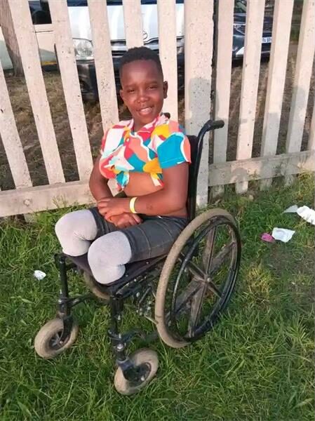 A young girl in a wheelchair sitting on the grass.