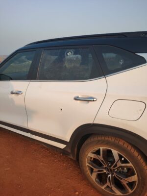 Damaged white SUV with cracked side window, parked on dirt road - Ridge Times news coverage.