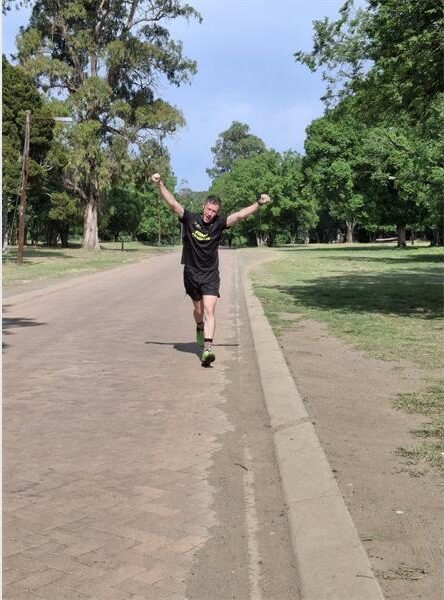 Man in black shirt and shorts holds up his hands.