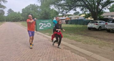 woman runs with two men holding up a with a number 250.