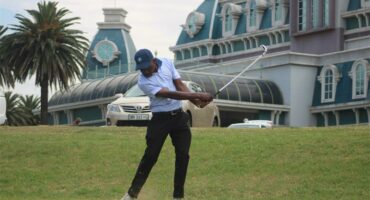 golf player tees off with the graceland casino in the background