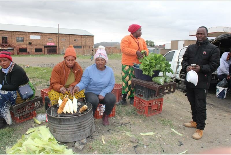Women braai mielies outside