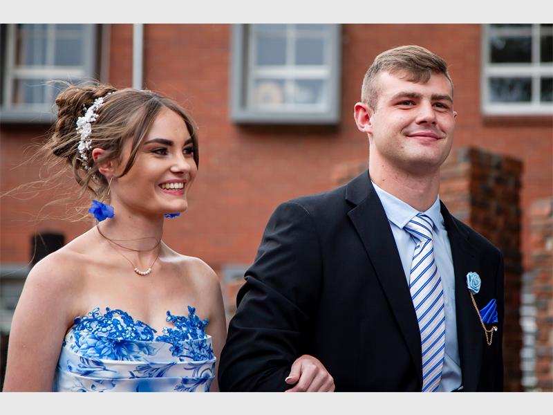 Girl in blue and white locks arms with boy in dark jacket and striped tie