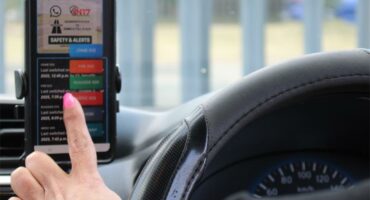 woman types in app on phone in car