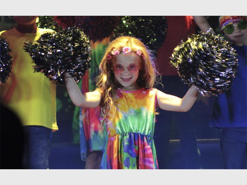 girl dressed in tie-dye with pom-poms