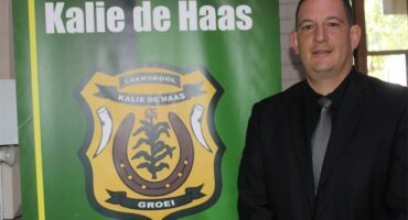 Man in front of a banner of Laerskool Kalie de Haas