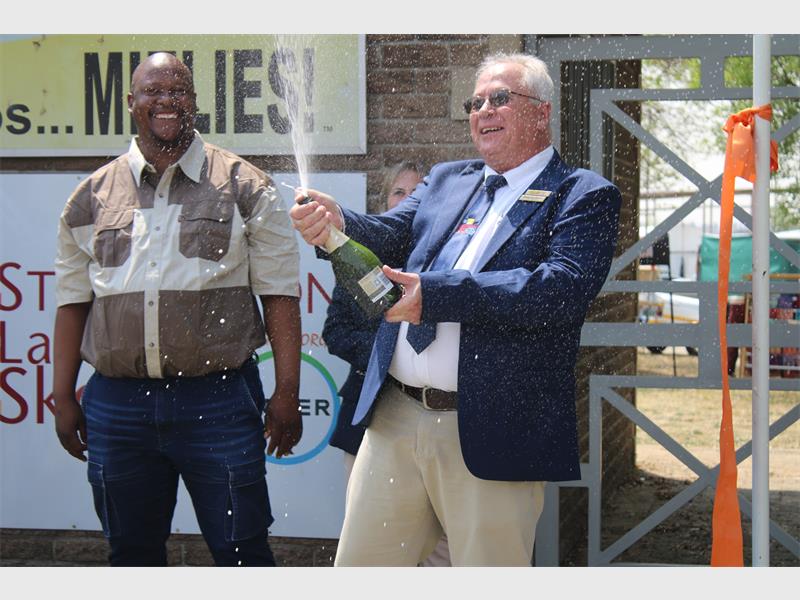 A man pops a bott;le of sparkling wine.