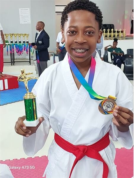 Karate student holds up trophy and medal
